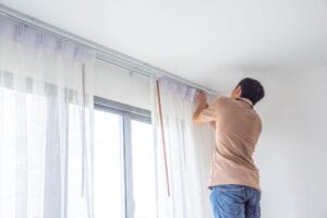 man fixing curtains