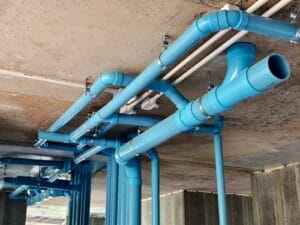 A bright blue pipes attached to a solid concrete wall